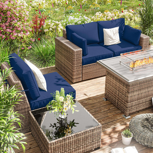 Outdoor patio seating set with blue cushions, rattan furniture, glass coffee table, and fire pit on wooden deck