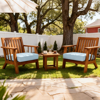 Outdoor wooden armchairs with sky blue cushions and a small wooden table on green lawn
