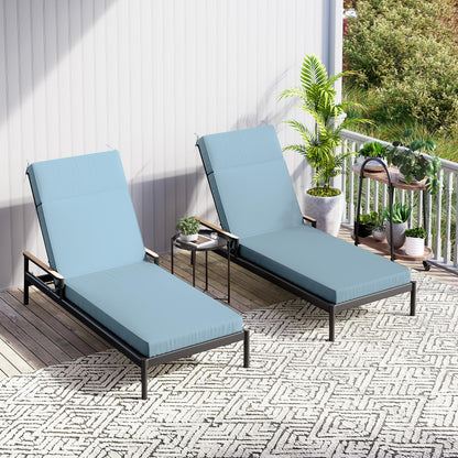 Two blue lounge chairs on a balcony with plants and a small table.