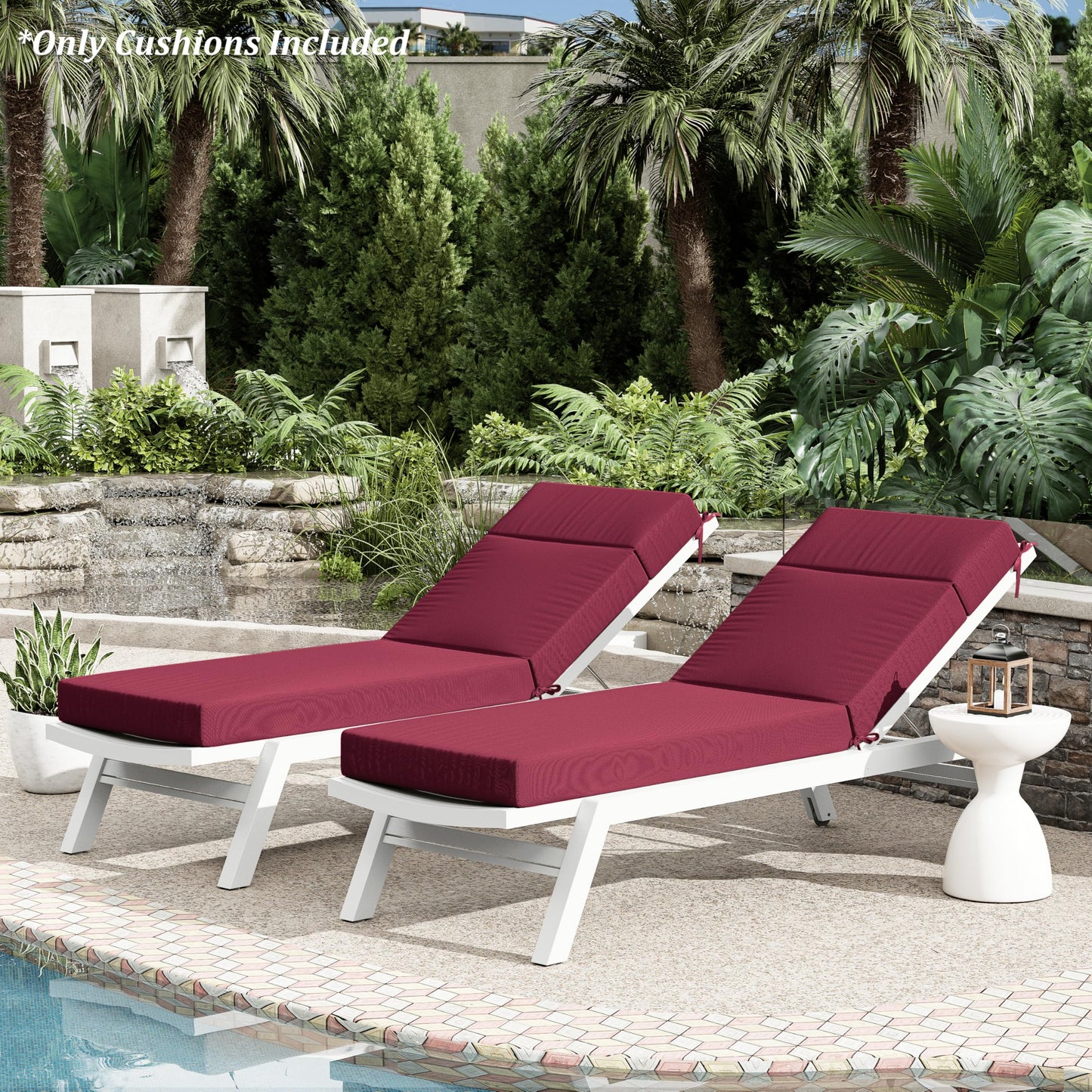 Two Burgundy cushioned lounge chairs by a pool with palm trees and greenery in the background.