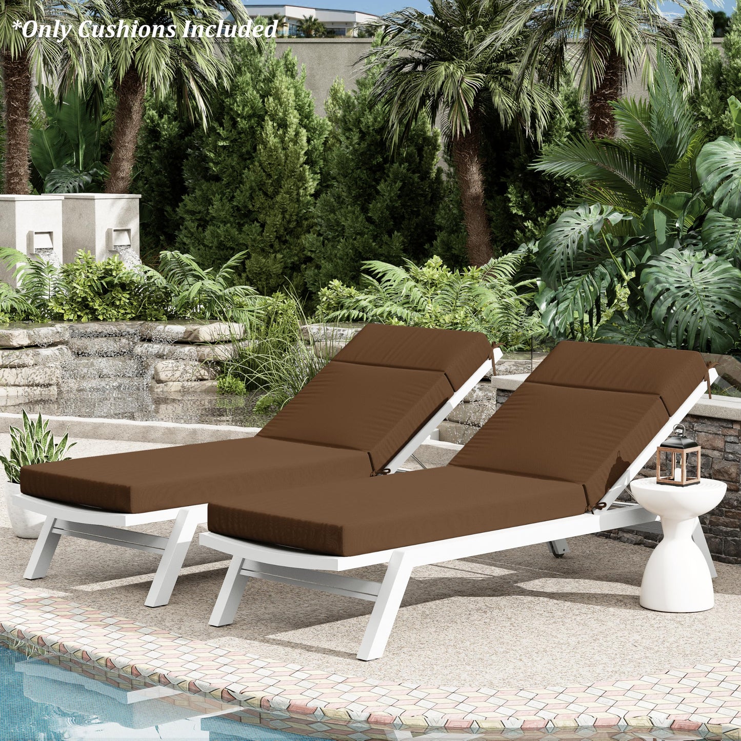 Two brown cushioned lounge chairs by a pool with palm trees and greenery in the background.
