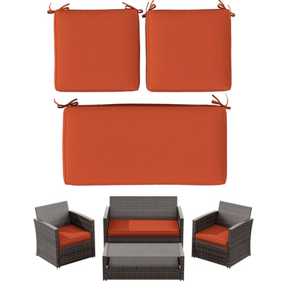 Set of three orange outdoor seat cushions for loveseat and chairs with dark wicker patio furniture
