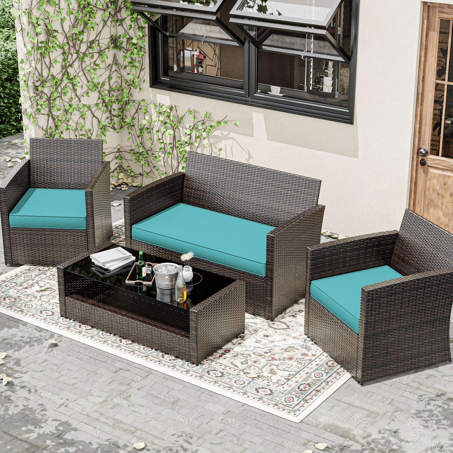 Outdoor rattan loveseat and chairs with turquoise cushions on a patterned rug in patio setting