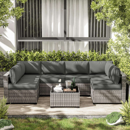 Gray outdoor sectional sofa with cushions on a wooden deck, surrounded by greenery.