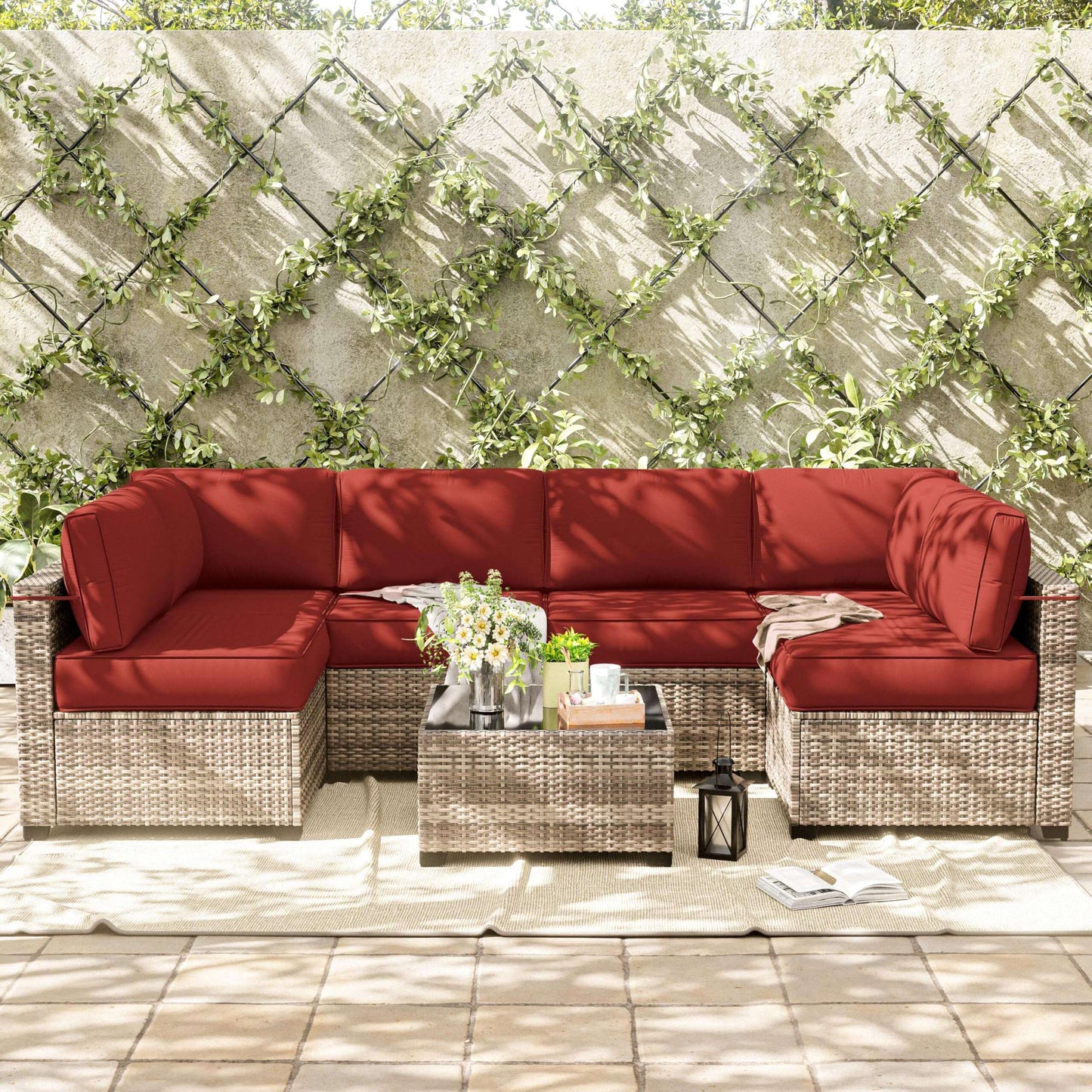 Outdoor patio set with red cushions against a stone wall with greenery