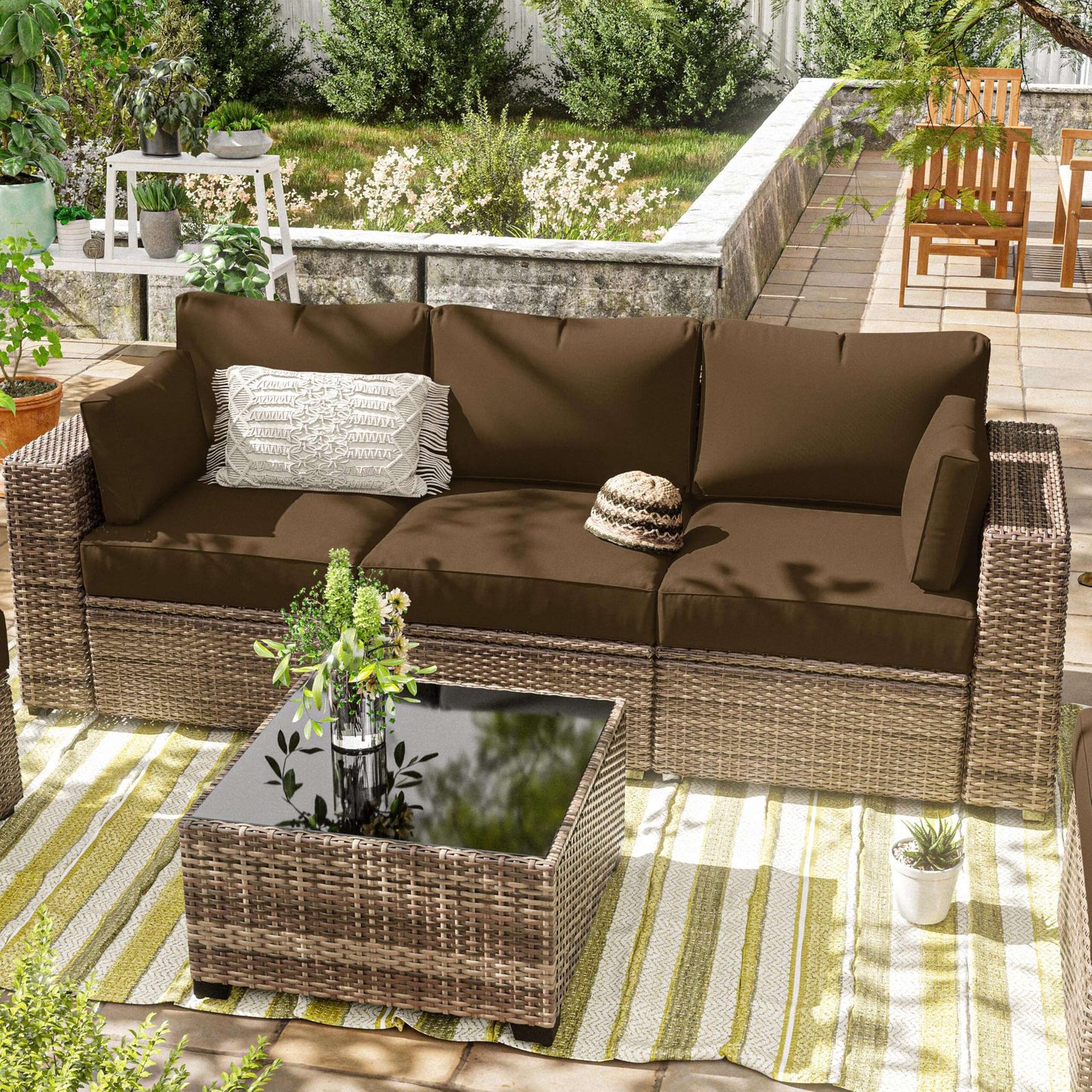 Outdoor patio with brown cushion covers on wicker sofa and matching wicker coffee table with glass top