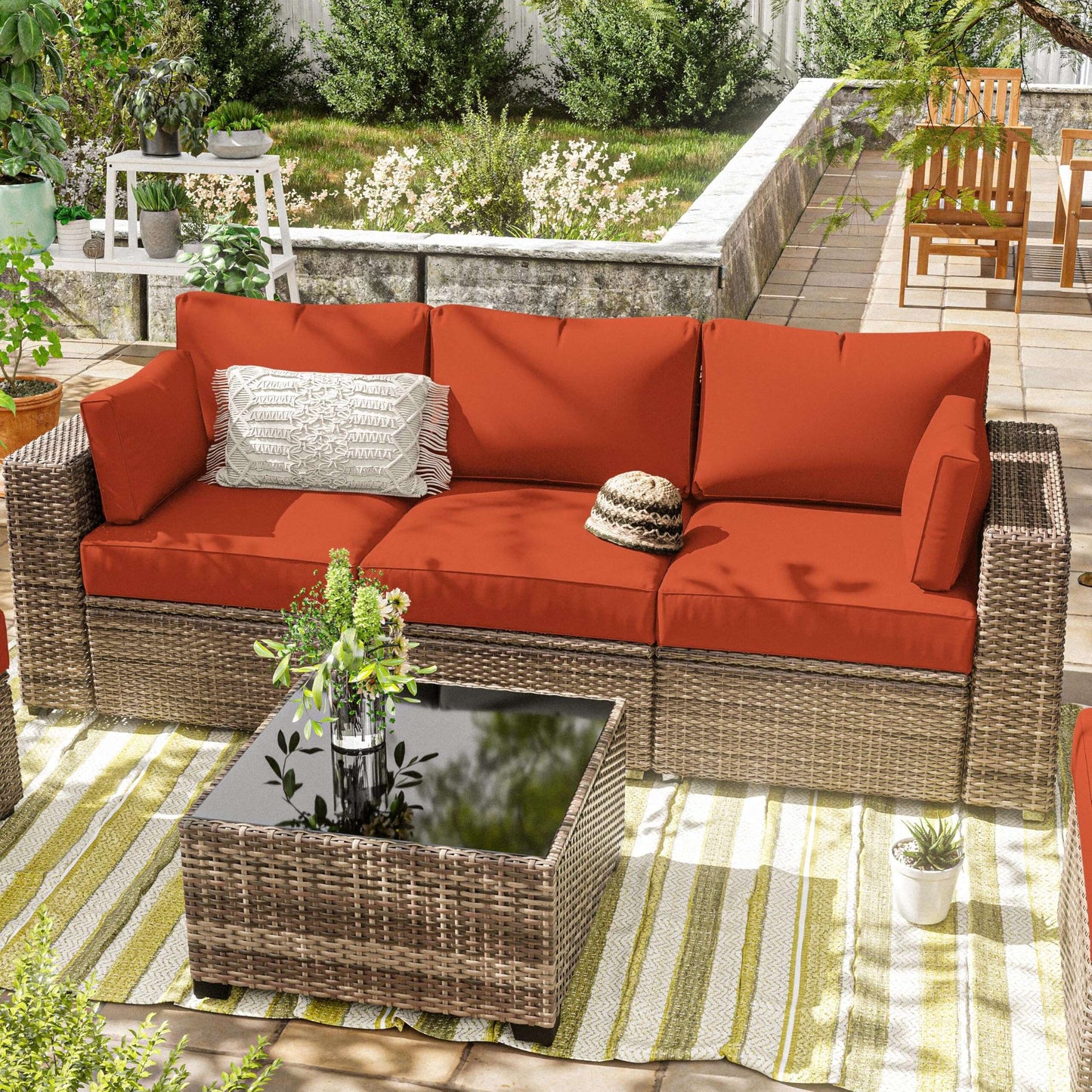 Outdoor patio with wicker sectional sofa featuring orange cushions and decorative pillows