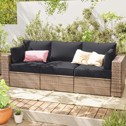 Outdoor sofa with grey cushions and decorative pillows on a wooden deck with plants around.