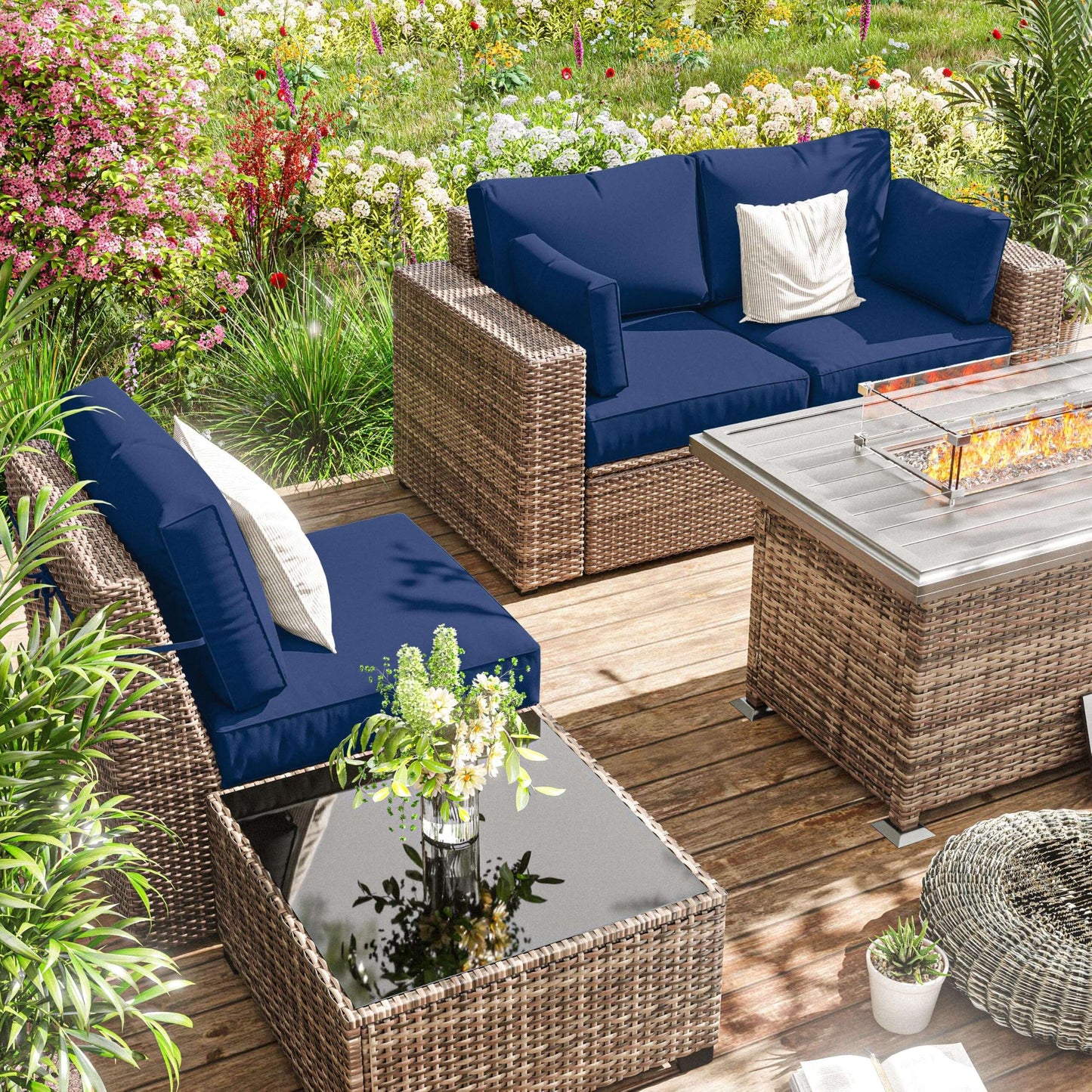 Outdoor patio seating set with blue cushions, rattan furniture, glass coffee table, and fire pit on wooden deck