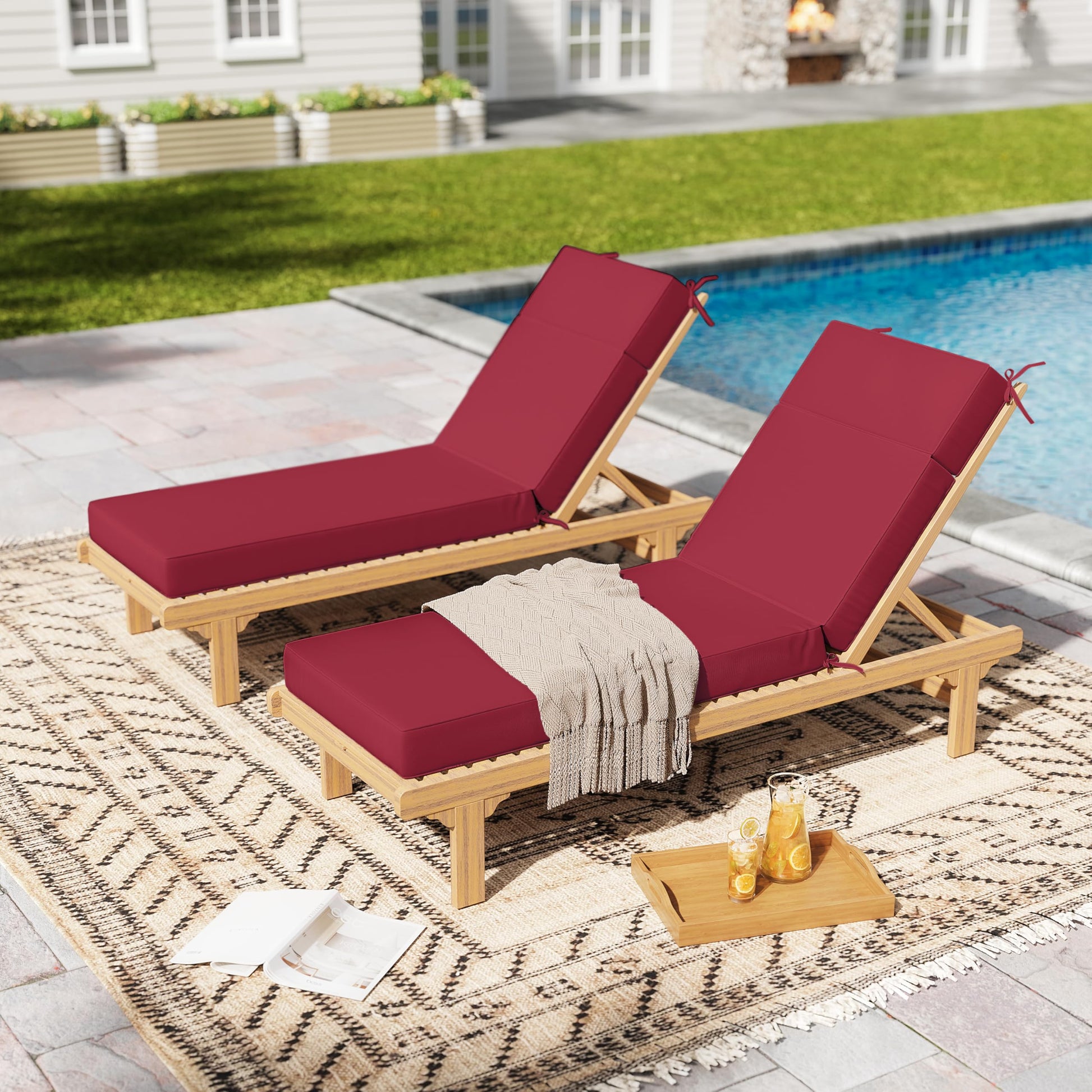 Two wooden lounge chairs with fuchsia red cushions by a poolside.