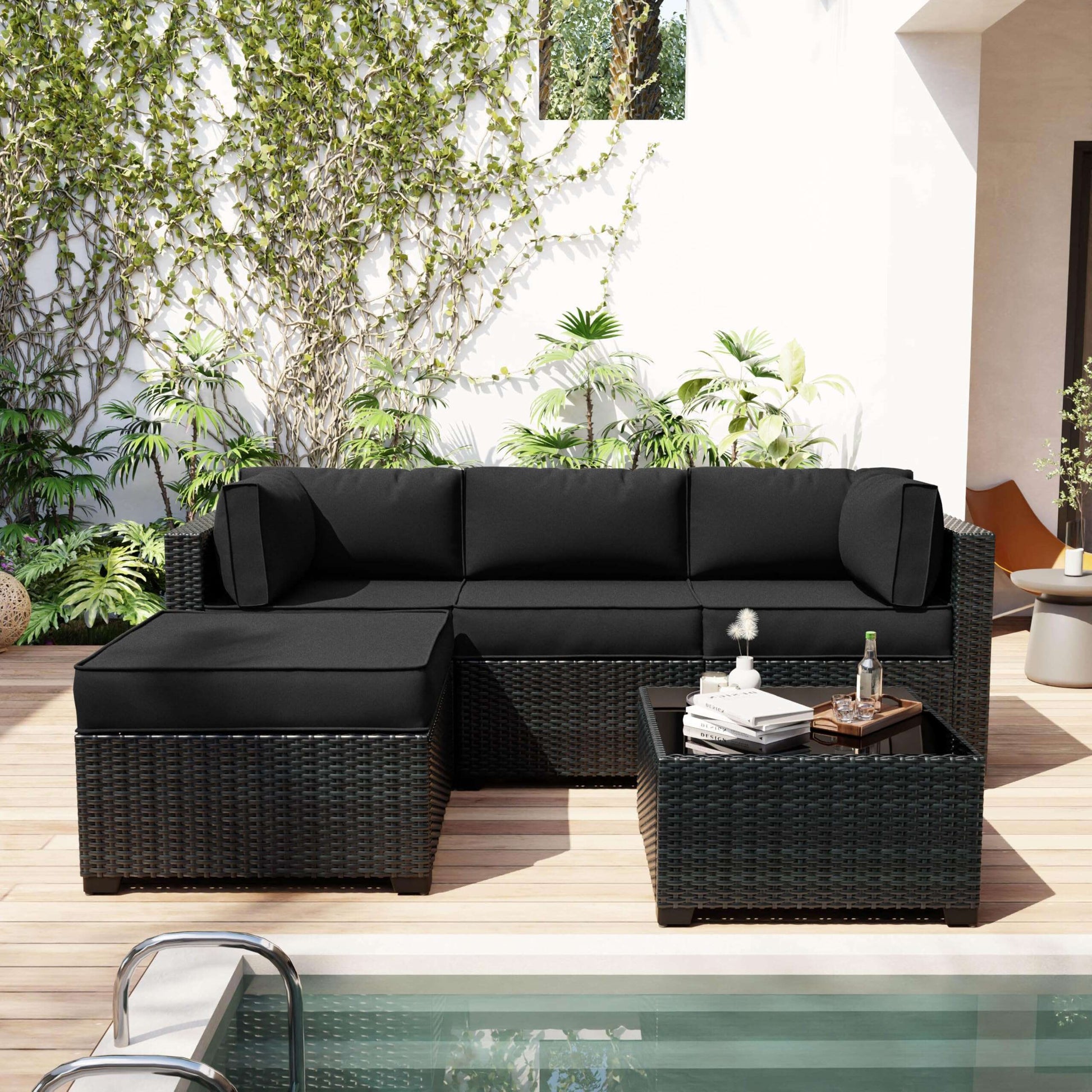 Black outdoor sectional sofa with a small table on a patio with plants in the background