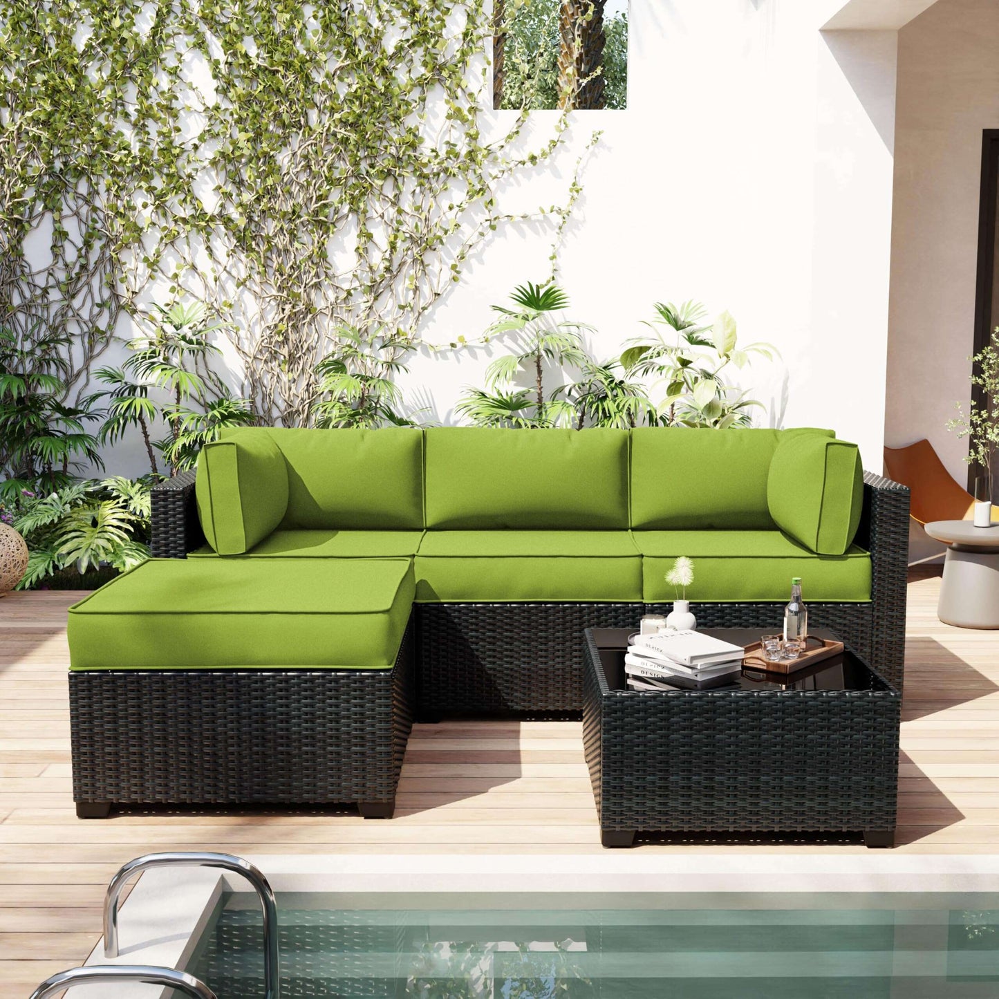 Green outdoor sectional sofa with cushions on a patio with plants and a pool.