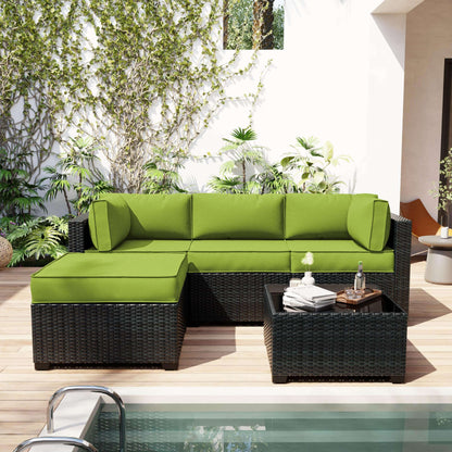 Green outdoor sectional sofa with cushions on a patio with plants and a pool.