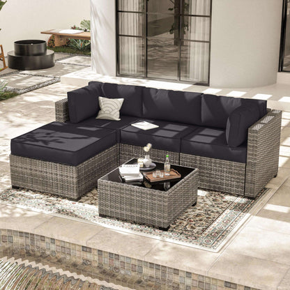 Modern outdoor patio set with gray wicker sectional sofa and black cushions on tiled terrace