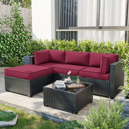 Outdoor patio furniture set with red cushions on a wooden deck.