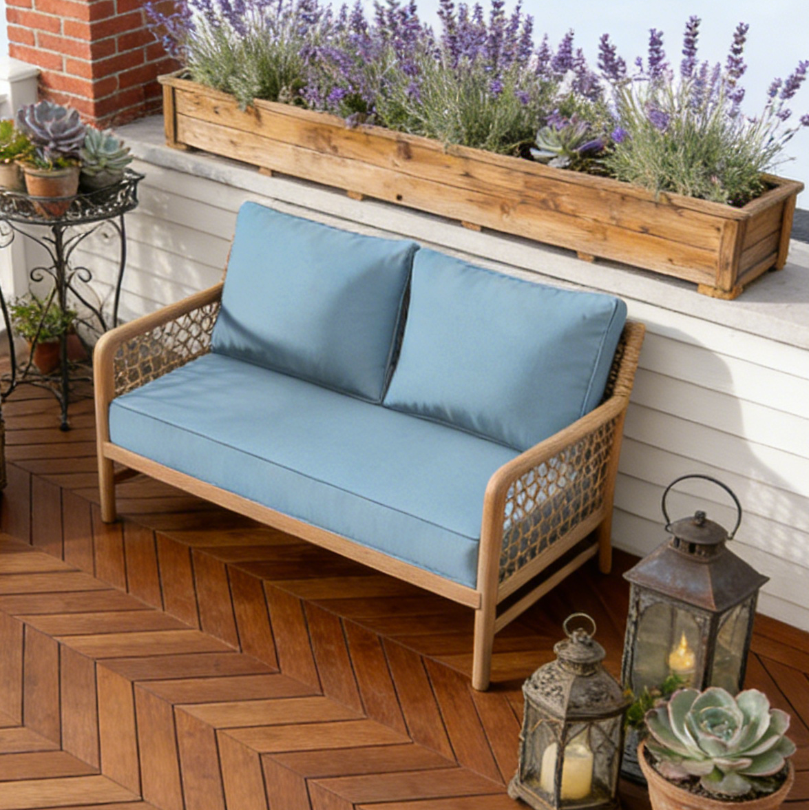 Wooden outdoor bench with blue cushions on a wooden deck with plants and lanterns.