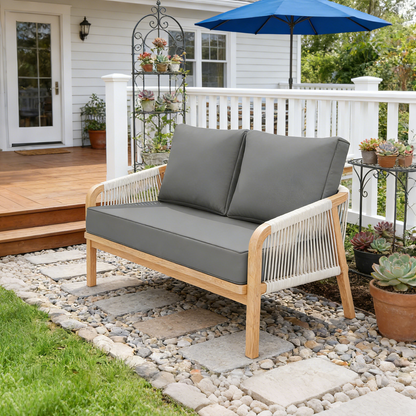 Outdoor patio set with gray cushions and a blue umbrella on a stone patio.