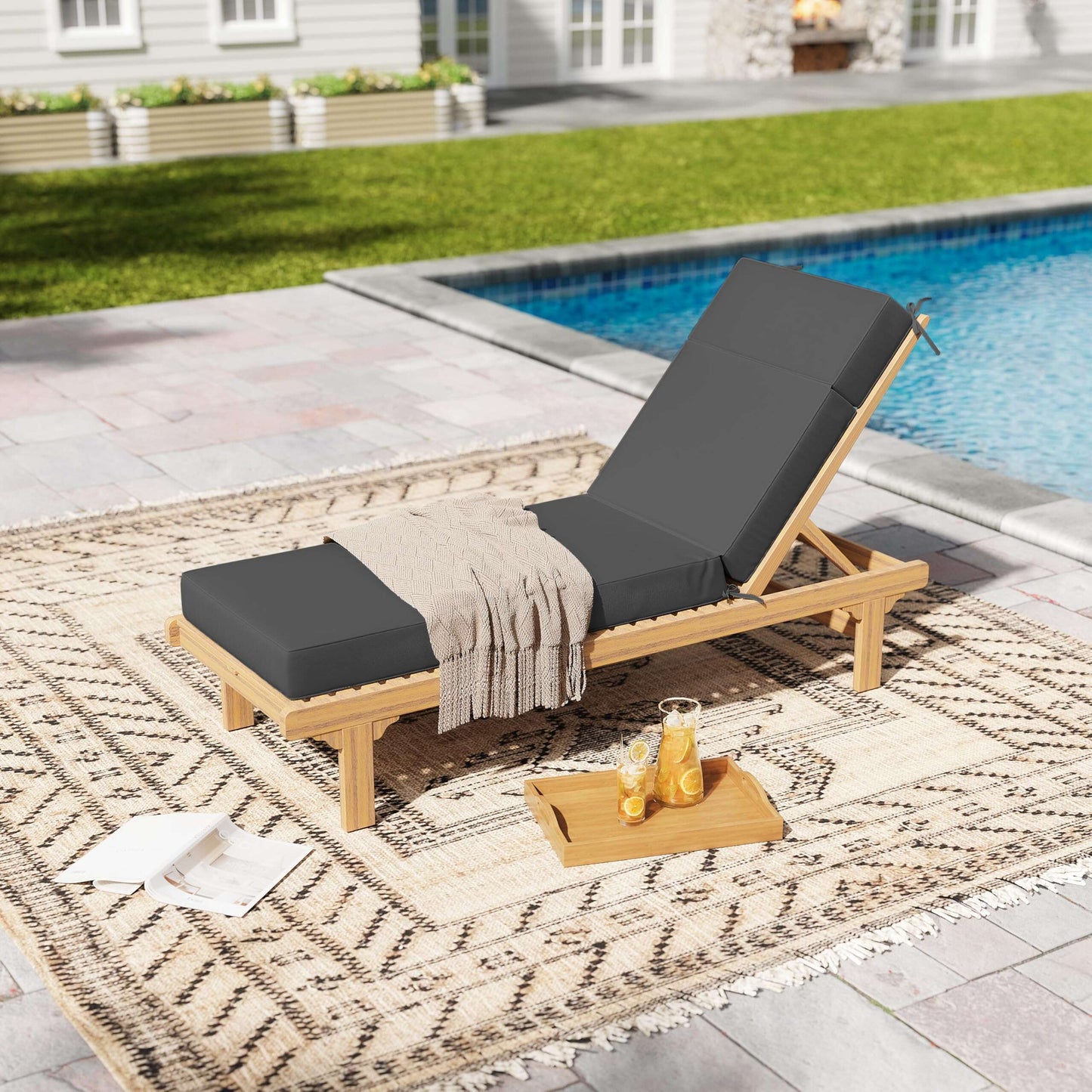 Wooden lounge chair with grey cushions by a poolside on a patterned rug.