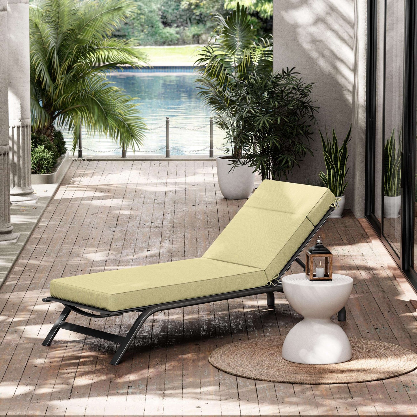 Outdoor lounge chair with yellow cushion on a wooden deck with plants and a pool view.