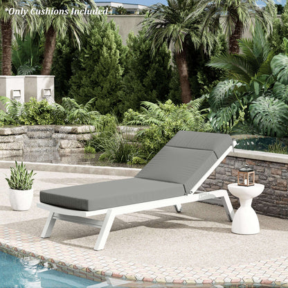 Gray cushioned lounge chair on a patio with pool and garden view