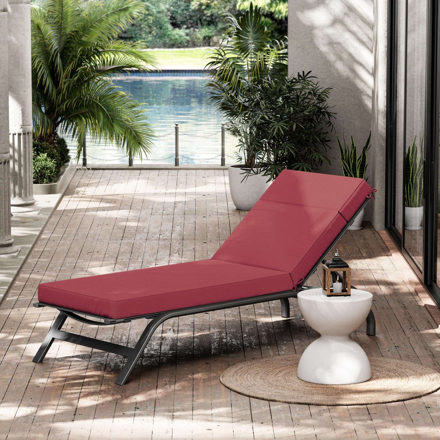 fuchsia red cushioned outdoor lounge chair on a wooden deck with plants and a pool in the background
