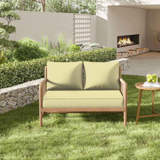 Outdoor patio set with yellow cushions on a grassy area, featuring a small table with apples and a fireplace in the background.