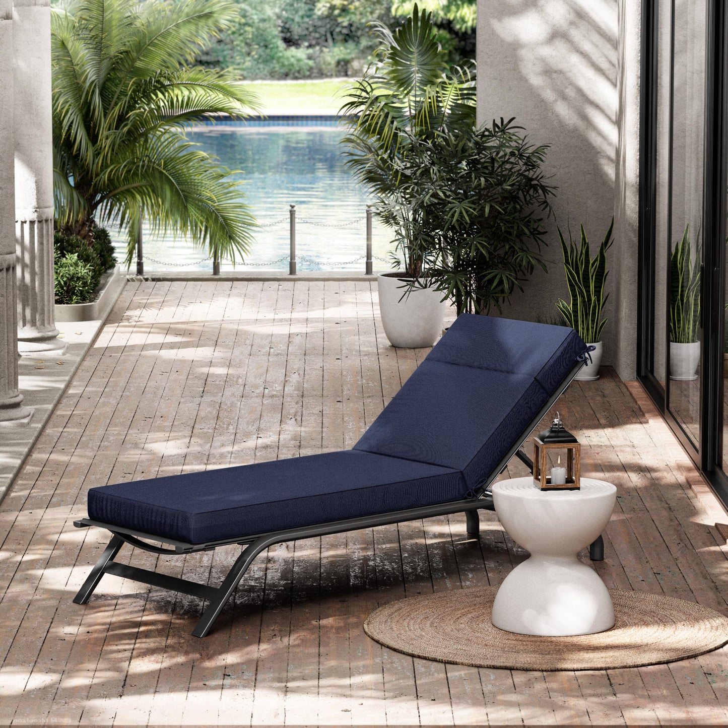 Navy blue outdoor lounge chair on a wooden deck with plants and a pool in the background