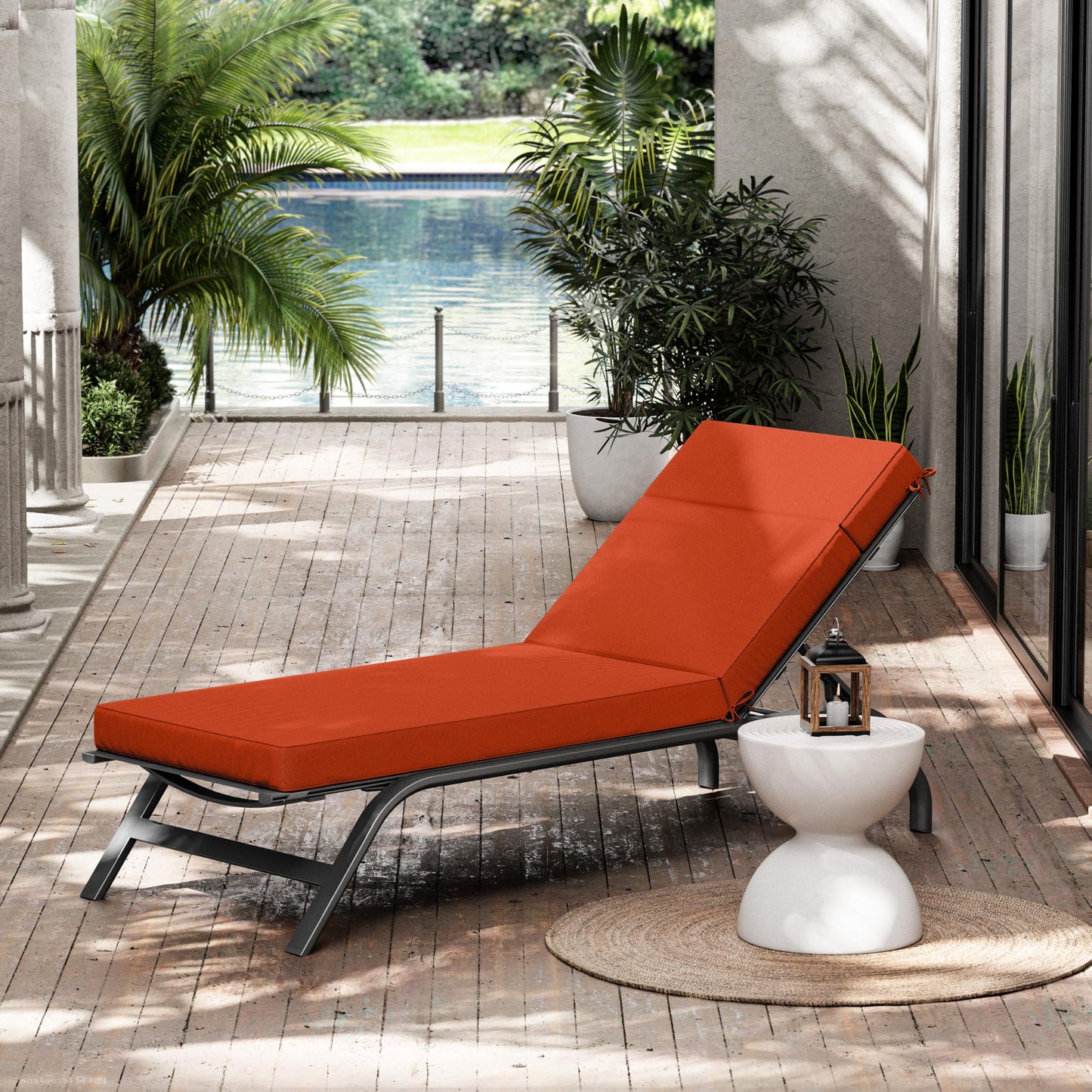 Orange outdoor lounge chair on a wooden deck with plants and a pool in the background