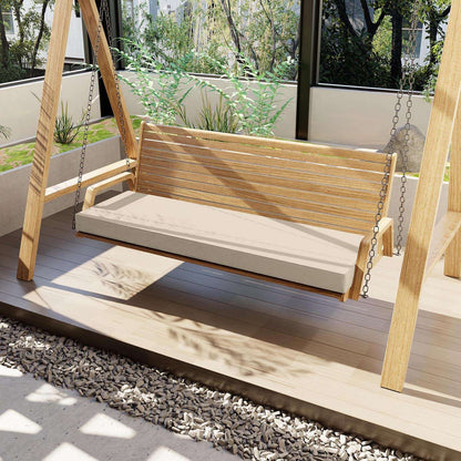 Wooden swing with a cream cushion on a wooden deck in an outdoor setting