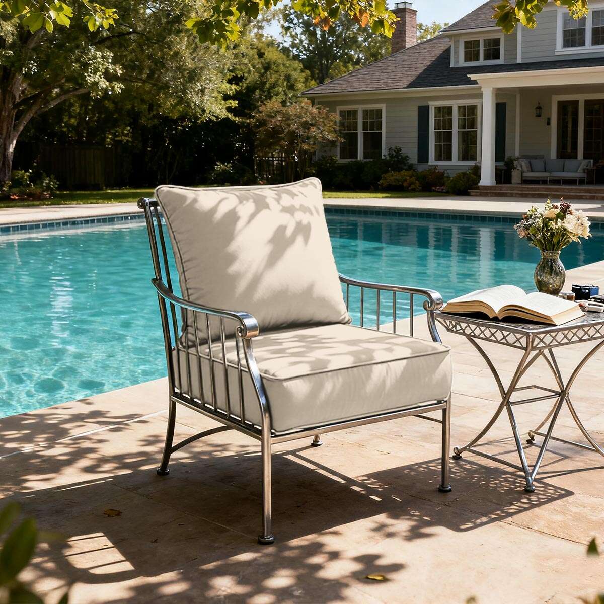 Patio chair with cushions by a poolside, featuring a house in the background.