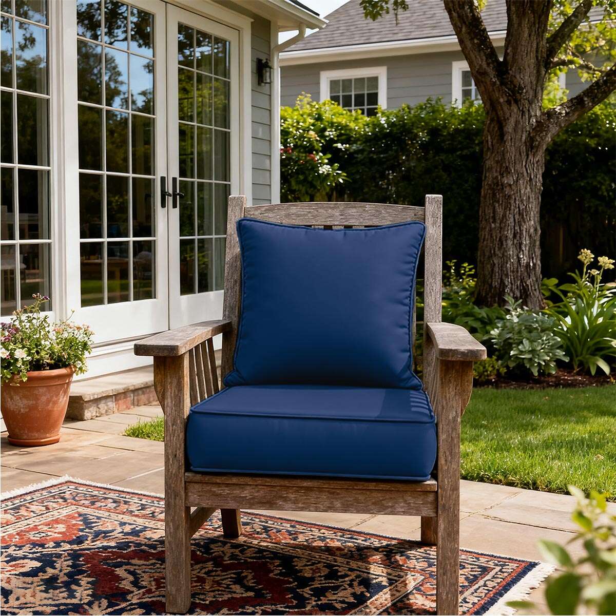 Wooden chair with blue cushions on a patio, surrounded by garden elements.