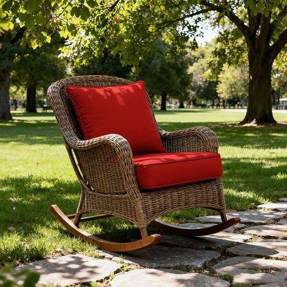 Wicker rocking chair with red cushions on a stone path in a park.