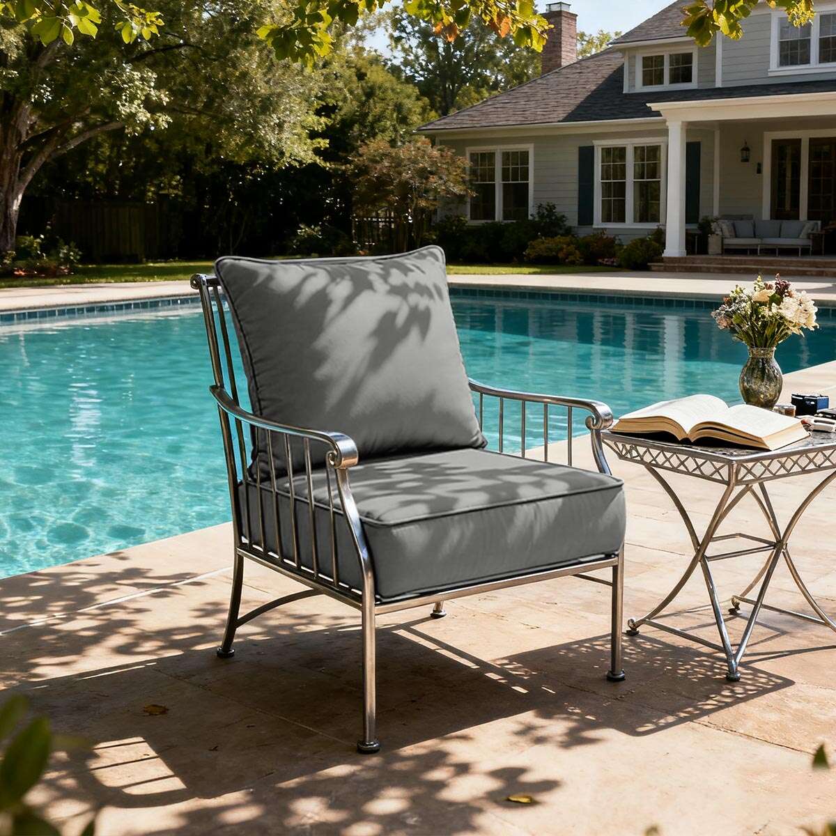 Outdoor chair with gray cushions by a poolside, featuring a house in the background.