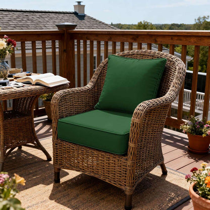 Wicker chair with green cushions on a wooden deck with tables and plants.