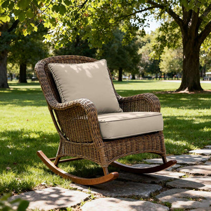 Wicker rocking chair with beige cushions on a stone path in a park.