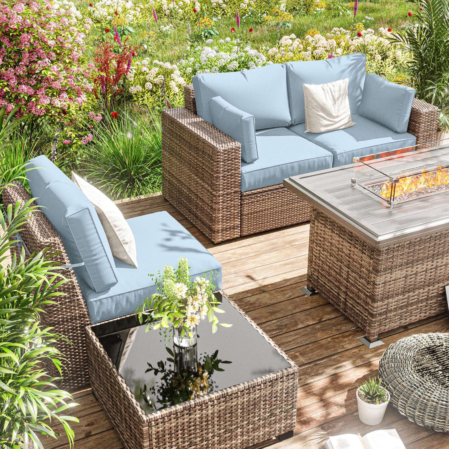 Outdoor patio set with wicker furniture and blue cushions in a garden setting.