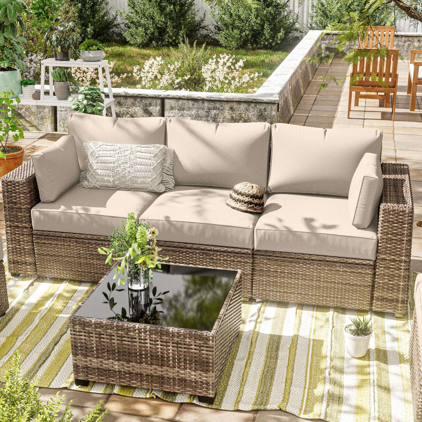 Outdoor patio set with wicker furniture and beige cushions on a striped rug.