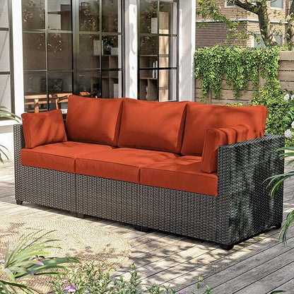 Outdoor 3-seat wicker sofa with orange cushions on wood deck patio surrounded by greenery