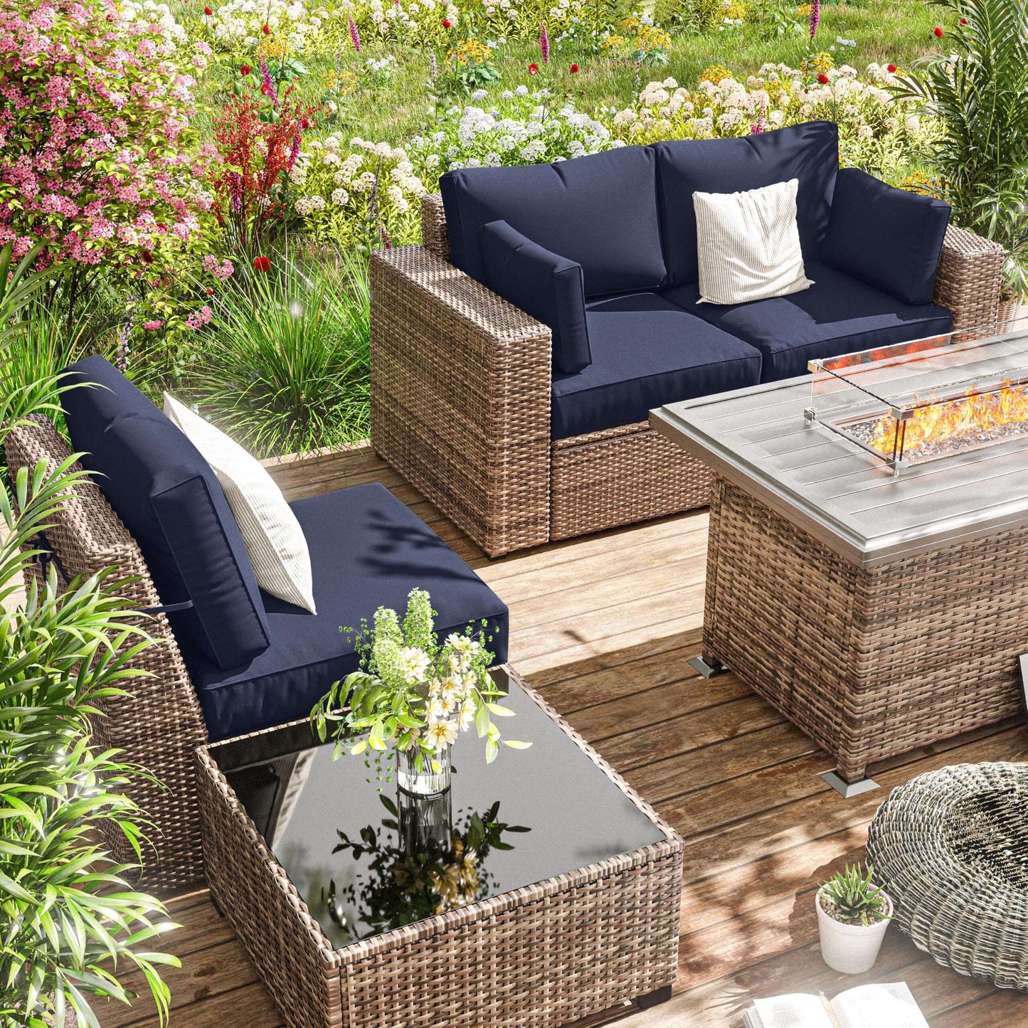 Outdoor patio furniture set with navy cushions on a wooden deck surrounded by flowers.