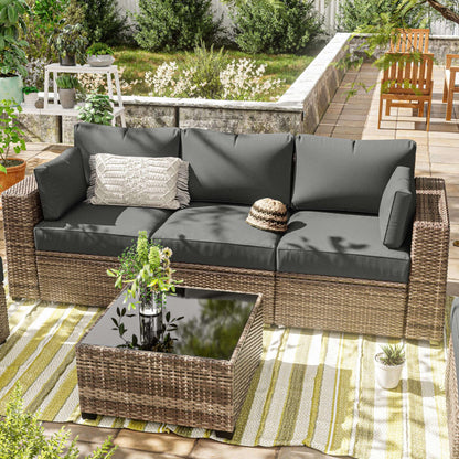 Outdoor patio set with wicker furniture and gray cushions on a striped rug.