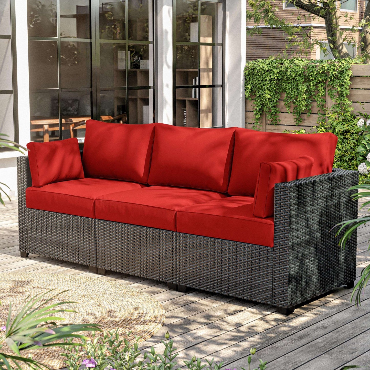Outdoor wicker sectional sofa with bright red cushions on wooden deck patio