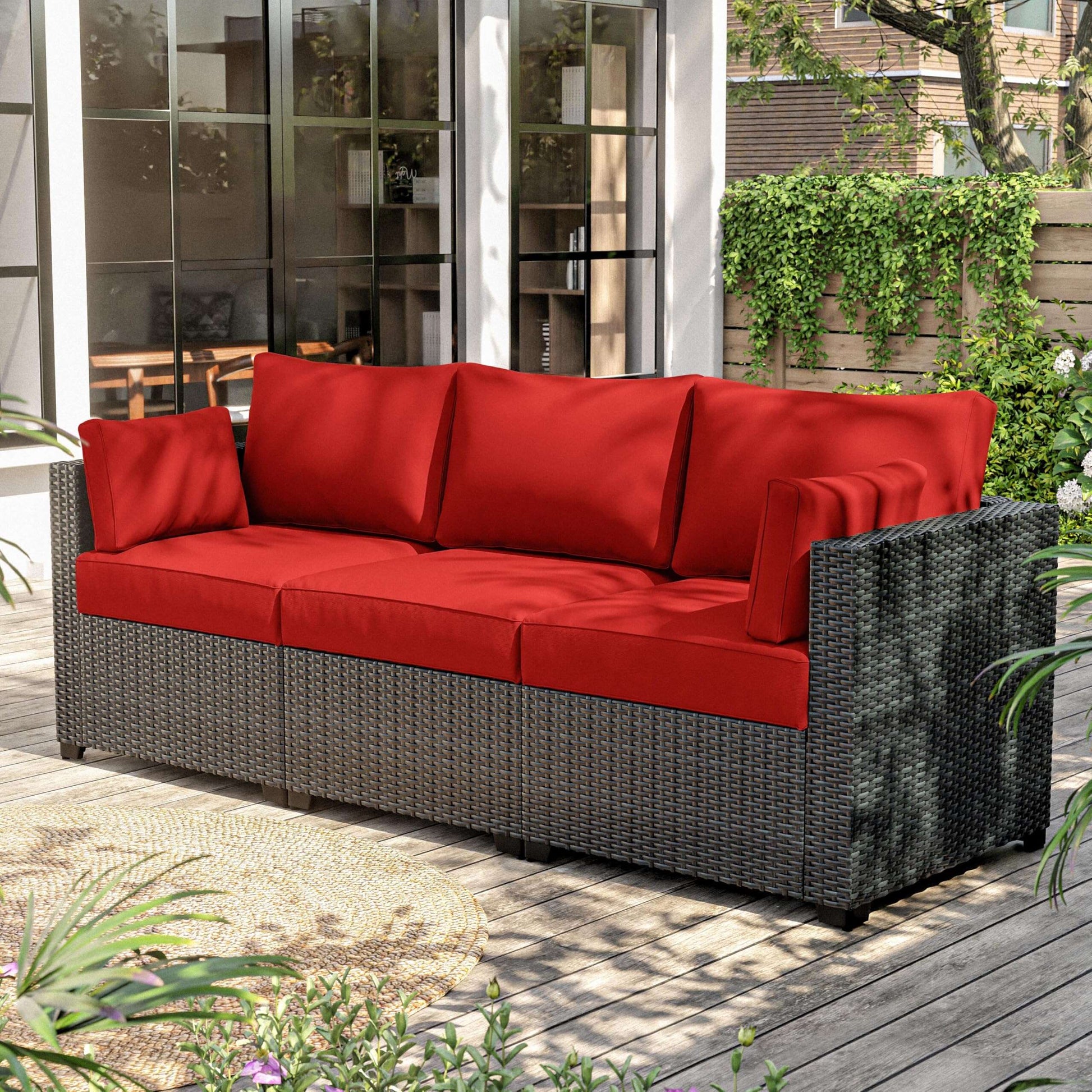 Outdoor wicker sectional sofa with bright red cushions on wooden deck patio