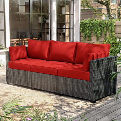 Outdoor wicker sectional sofa with bright red cushions on wooden deck patio