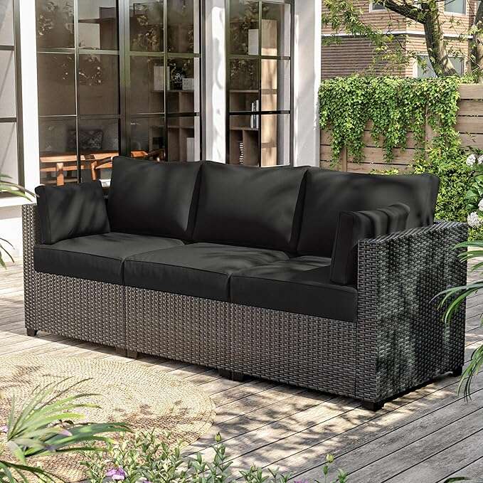 Modern outdoor three-seat sofa with black cushions and woven rattan frame on wooden patio