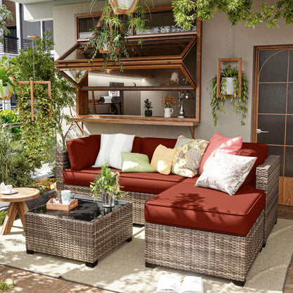 Outdoor patio with wicker sectional sofa and terra cotta cushions surrounded by greenery and hanging plants