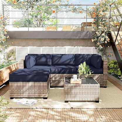 Navy blue outdoor sectional with wicker frame on a patio with plants and coffee table.
