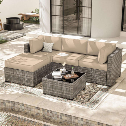 Modern outdoor patio with gray rattan sectional sofa, beige cushions, and wicker coffee table