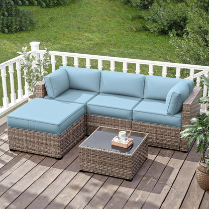 Outdoor wicker sectional sofa with sky blue cushions on wooden deck patio with glass-top coffee table