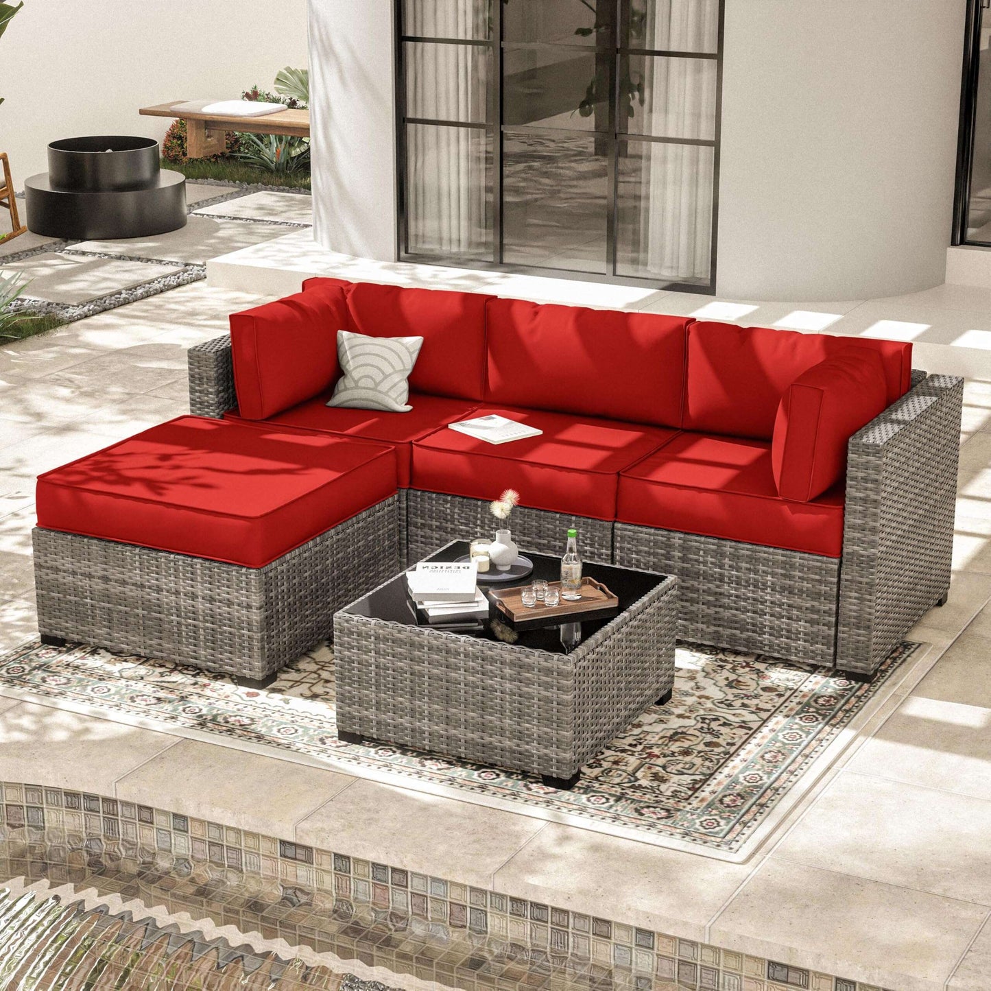 Modern outdoor patio with gray wicker sectional sofa with red cushions and a matching coffee table on a patterned rug