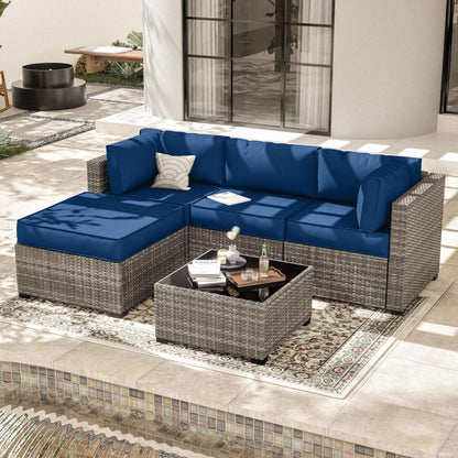Outdoor patio with gray wicker sectional sofa featuring blue cushions and a matching coffee table on decorative rug